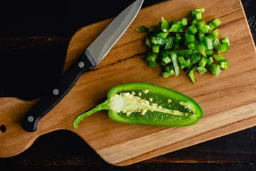 Fotobehang Diced Jalapeno Pepper on a Wood Cutting Board: Finely chopped chili pepper with a paring knife on a wooden cutting board © Candice Bell