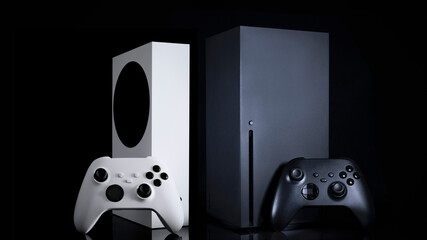 White and black game consoles and controllers with black background