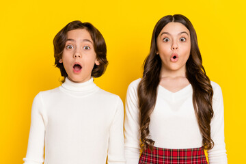 Photo portrait of children amazed staring with opened mouth isolated on vivid yellow color background