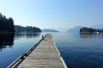 Fototapeta na wymiar A beautiful view of a long empty dock extending into the ocean waters of the sunshine coast, in Egmont, British Columbia, Canada