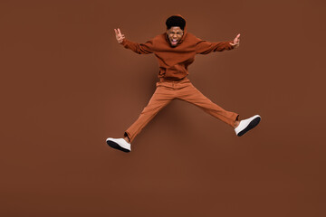 Fototapeta na wymiar Full size photo of cool yell short hairdo young guy jump dress sportswear trousers sneakers isolated on brown background