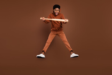 Fototapeta na wymiar Full size photo of stressed short hairdo young guy hold bit jump dress sportswear trousers sneakers isolated on brown background