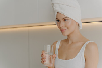 Image of young beautiful woman with fresh and glowing skin with glass of pure water