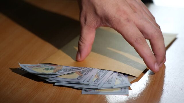 Man pick up Brown document envelope with dollar money before leave the house. Hand male hold Brown envelope on wood table. Concept travel, tourism Eating out and shopping.4K 2160p 30fps UltraHD footag