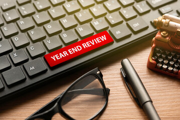 Glasses,pen, miniature typewriter and computer keyboard with red button written with Year End...