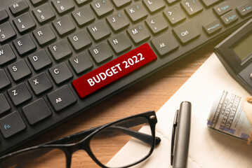 Glasses,pen,book,money, calculator and computer keyboard written with Budget 2022.