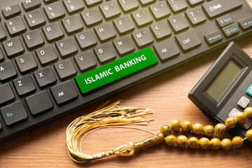 Calculator, rosary beads and computer keyboard with green button written with Islamic Banking.