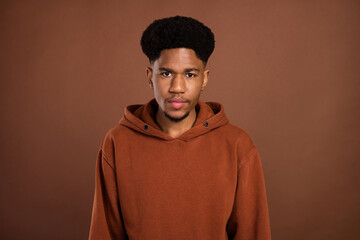 Photo of calm focused serious handsome african guy look camera wear hoodie isolated on brown background