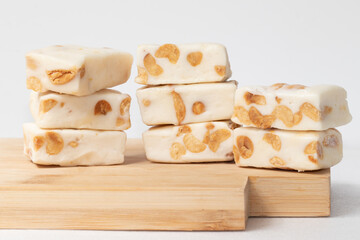 A pile of nougat squares on cutting board.