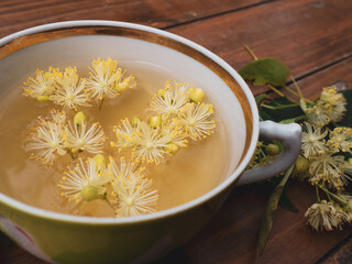 Cup of green tea and linden on wooden background, useful linden flowers folk medicine concept
