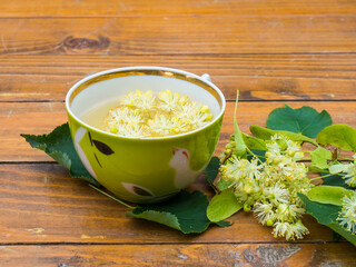 Cup of green tea and linden on wooden background, useful linden flowers folk medicine concept