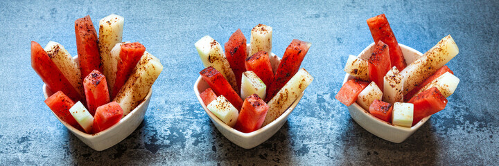 Fruit sticks with chili spice. Fresh raw sweet cut fruit with spicy chile and cocoa condiment powder. Summer snack.