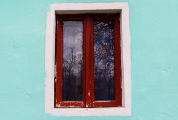 Traditional wooden window of a rustic house. Brown wooden window and a light blue wall