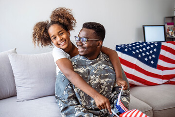 Happy little girl daughter with American flag hugging father in military uniform came back from US army, view of dad male soldier reunited reunited with family at home - obrazy, fototapety, plakaty