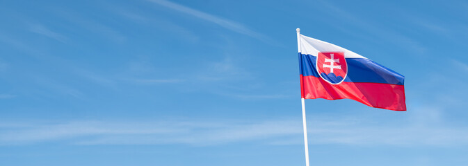 Slovak flag waving in wind and sunlight. Flag of Slovakia on blue sky background. Empty copy space for text.
