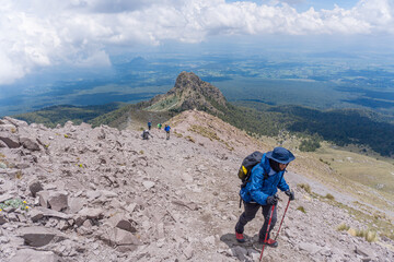male with a backpack hiking and climbing to the top of malinche volcanic mountain in Mexico