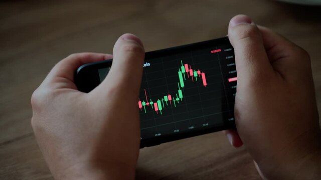 Graph of crypto currency online. Man holding smartphone and looking on Quotes of eth and btc at stock exchange. Stock exchange market chart of ethereum. View at the app on the screen of the phone