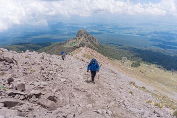 male with a backpack hiking and climbing to the top of malinche volcanic mountain in Mexico