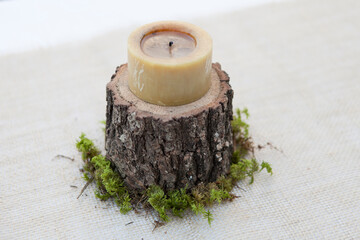 vela natural sobre un tronco cortado para levantar la vela de la mesa con un poco de musgo en el mantel  - obrazy, fototapety, plakaty