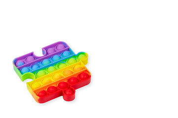 Silicone toy antistress pop it. Rainbow anti-stress toy fidget in puzzle shape isolated on white background. Copy space.