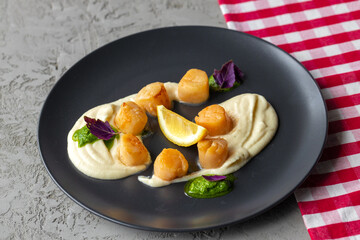 Scallops in creamy sauce on black plate