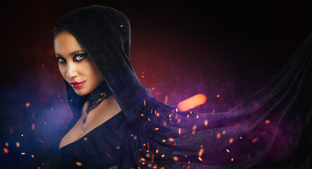 fantasy gothic woman dark witch. Black-haired evil girl demon in black dress cape hood with fire sparks. Helloween concept