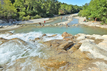 blue water of a river  with in the background and not recognizable, a group of children in the water
