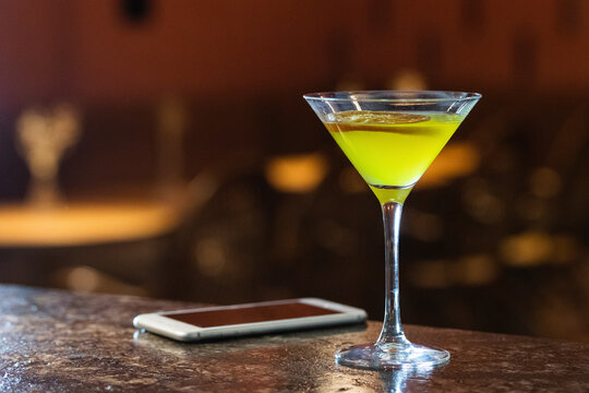 Drink in martini glass by mobile phone on table