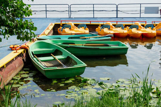 Boat station on the lake. Boats and pedal boats on the water. Water lilies grow in the water.