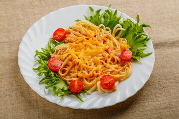 A plate of pasta with cherry tomatoes and cheese on a linen tablecloth.