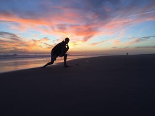Crouching silhouette over colorful sunset