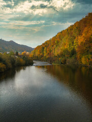 Calm dark river in a dense forest in fall