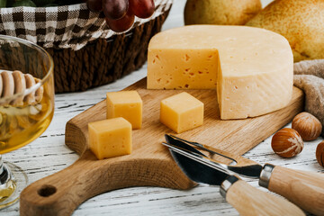 Cheese dish with organic cheeses, fruits, nuts on a wooden background. Delicious cheese snack
