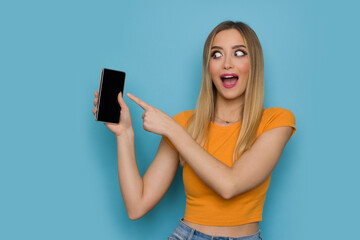 Excited Young Woman Is Holding Telephone And Pointing At It