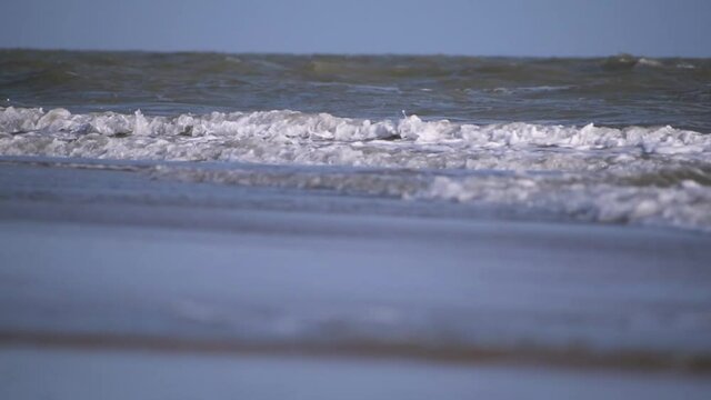 sea waves crashing at the beach at Mandvi at Kutch, Gujarat, India. Beautiful tropical beach with blue sky with waves crashing empty beach during summer