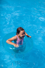 the concept of a summer holiday, a cheerful child has a good time in the clean, transparent water of the hotel pool. 