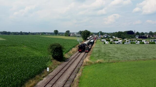 Dutch steam locomotive with wagons driving through Veluwe landscape