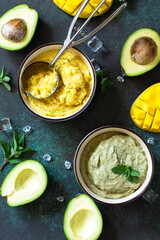 Diets vegetarian summer Ice cream or sorbet, sweet snack or dessert. Homemade avocado and mango fruit ice cream, tropical fruit sorbet on a dark stone table. Top view flat lay background.