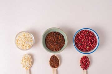 Colourful set different spices for meat, vegetarian dishes on light background. Seasoning pink peppercorns, dried onions, sun dried tomatoes. Hot spicy background for cooking. Interesting soup taste
