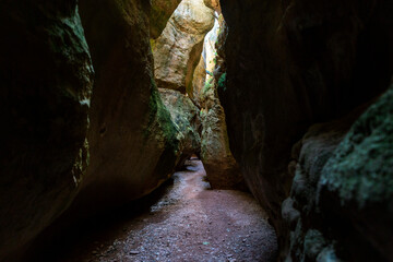 spectacular cave interior with large rocks and entrance from the top of sunlight rays.