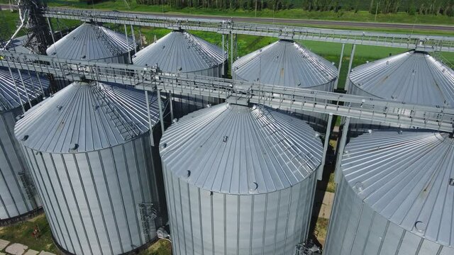 Round aluminum granaries. Large silver bins for processing grains. Exterior of a modern silos. Grain elevators for keeping crop. Aerial view