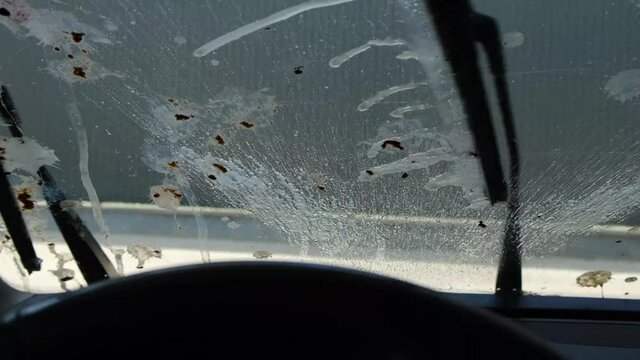 The windshield of a car with lots of bird droppings.