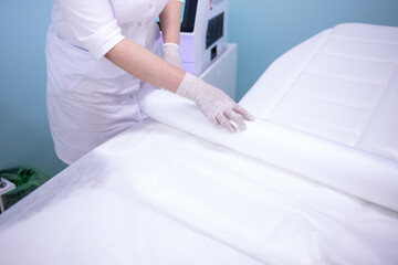 A female doctor in a white coat makes a hospital bed.