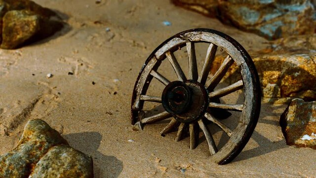 Old wooden cart wheel at sand beach