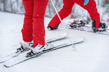 Legs of skier and snowboarder in bright red tracksuits standing on ski slope. Selective focus. Winter sport