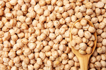 Closeup view of raw chickpea beans. Uncooked chickpeas in wooden spoon. Healthy eating