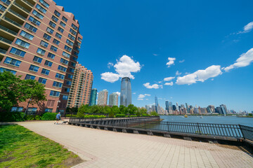 Unique shape clouds float over the Luxury high-rise apartments in Jersey City New Jersey ward and Lower Manhattan skyscraper in Manhattan ward along the promenade beside Hudson River in springtime.