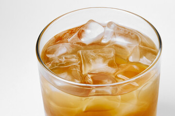 glass with a drink of dark color with ice, on a white background, alcohol
