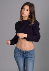 Standing Woman in Cropped Blue Sweater and Jeans - obrazy, fototapety, plakaty