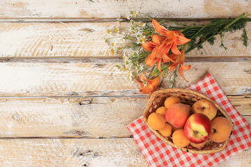 Summer berries and fruits on a wooden background with lilies and daisies, harvesting in the village, healthy natural food concept, breakfast with ingredients, store advertisement